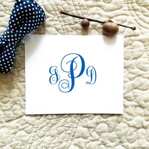 May include: A white card with a blue monogram of the letters "S P J" in a cursive script font.