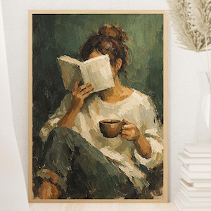 Puede incluir: Una pintura al óleo en un marco de madera que representa a una persona con cabello castaño recogido en un moño, vistiendo una camisa blanca de manga larga y pantalones oscuros. Sostiene un libro blanco abierto y una taza marrón.