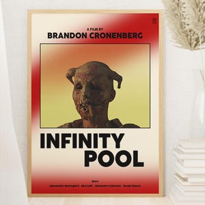 May include: A framed movie poster for "Infinity Pool" by Brandon Cronenberg. The poster features a grotesque, unsettling face against a red and yellow gradient background. The film's title is boldly displayed in black, with the cast listed below.