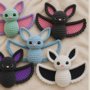 Puede incluir: Cinco murciélagos de peluche tejidos a ganchillo en varios colores, incluyendo verde menta, negro, azul claro y blanco. Cada murciélago presenta grandes ojos oscuros, una pequeña nariz rosa y alas anchas con colores interiores contrastantes.