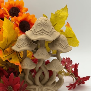 May include: A beige, 3D-printed sculpture featuring a cluster of five mushrooms with spiraled, layered caps and intertwined stems. The mushroom caps display a distinct geometric pattern with circular centers, all resting on a solid, curved base.