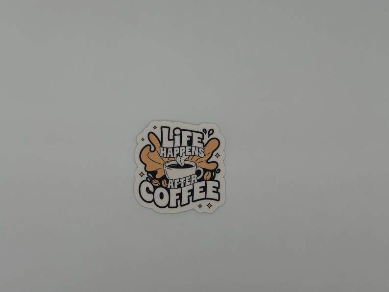 May include: A die-cut sticker featuring a central illustration of a steaming coffee cup surrounded by tan abstract shapes and coffee beans. The text reads Life Happens After Coffee in bold black lettering with small star accents on a white background.