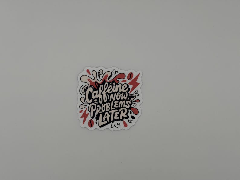 Puede incluir: Una pegatina troquelada con el texto negro Caffeine NOW, PROBLEMS LATER en un estilo de letra a mano audaz. El dise&ntilde;o est&aacute; acentuado con salpicaduras abstractas rojas y crema, formas de rayos y peque&ntilde;os iconos de granos de caf&eacute;.