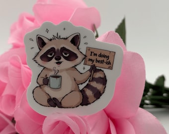 Grappige sticker met een wasbeer en koffie | Slaperig dier vinyl sticker (5,5 cm hoog × 5,05 cm breed)