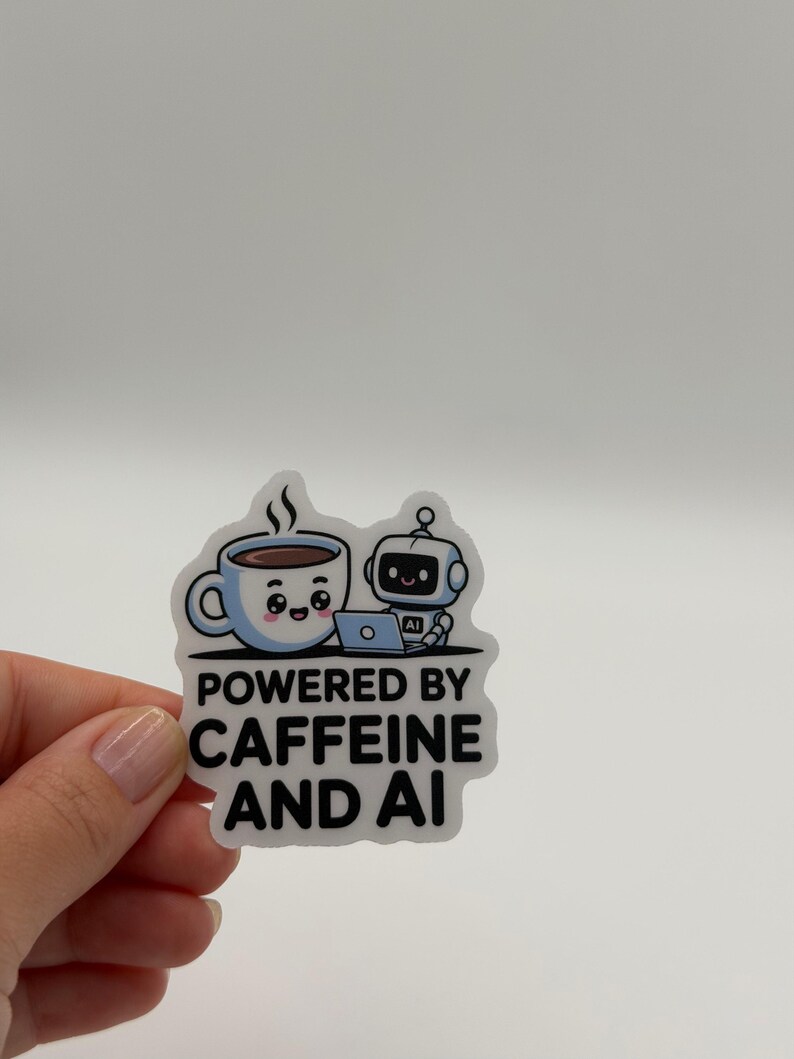 May include: A die-cut sticker featuring a light blue cartoon coffee mug with a smiling face next to a small white robot using a laptop. The text below reads POWERED BY CAFFEINE AND AI in bold black capital letters against a white background.