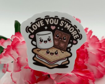 Puede incluir: Una pegatina troquelada que muestra un s'more, un malvavisco y una tableta de chocolate de dibujos animados con caras sonrientes. El texto "LOVE YOU S'MORE" está impreso en letras marrón oscuro con pequeños corazones rosas y destellos.