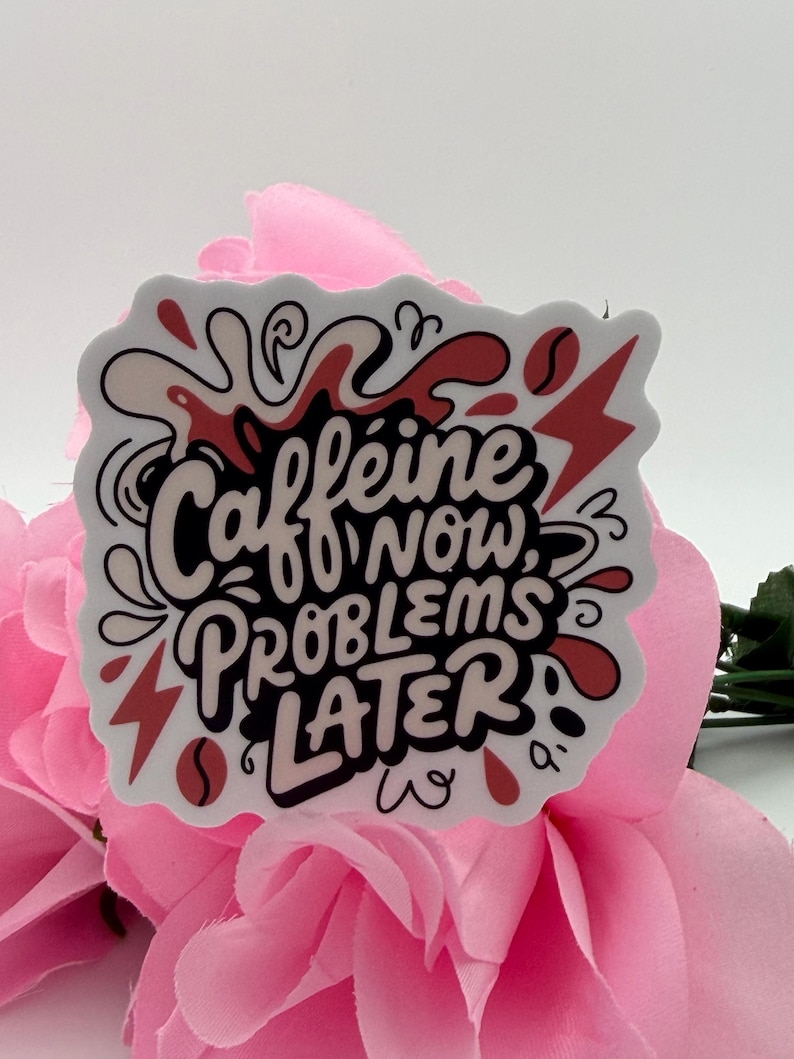 Puede incluir: Una pegatina troquelada con el texto en negro Caffeine NOW, PROBLEMS LATER. El dise&ntilde;o incluye salpicaduras de l&iacute;quido abstractas, granos de caf&eacute; y formas de rayos rojos sobre un fondo blanco, creando una visualizaci&oacute;n gr&aacute;fica y audaz.
