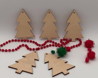 May include: Five flat, light-colored wooden Christmas tree cutouts with small holes at the top for hanging. The set is arranged with a string of shiny red beads and several small, fuzzy red and green pom-poms scattered around the wooden shapes.