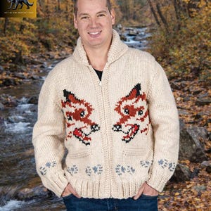 May include: Cream-colored zip-up cardigan sweater with a shawl collar and two front pockets. The sweater features a red, black, and white wolf design on the chest. The sleeves and pockets have a blue floral pattern. The logo "CARDIGAN WOLF" is in the upper left corner.