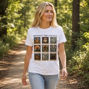 Può includere: Una t-shirt bianca a maniche corte con una griglia di nove illustrazioni quadrate di creature leggendarie e alieni con il testo "RESPECT THE LOCALS" in alto. Ogni quadrato contiene una creatura unica e una didascalia associata.