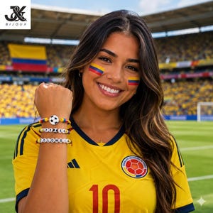 Könnte beinhalten: Eine Frau trägt ein gelbes Fußballtrikot mit der Nummer 10 und dem Wort "COLOMBIA" auf einem Armband. Die Armbänder haben einen Fußball und die Zahlen "22186". Der Hintergrund zeigt ein Fußballstadion.
