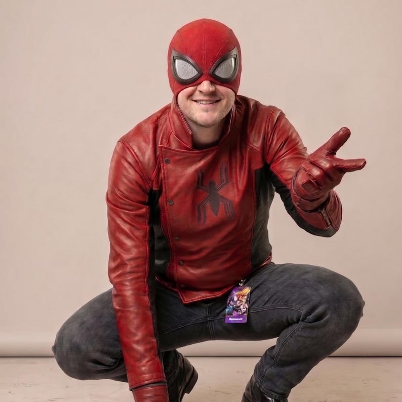 Puede incluir: Un disfraz de Spider-Man rojo y negro, que incluye una m&aacute;scara con grandes lentes oculares blancas, una chaqueta de cuero roja con un emblema de ara&ntilde;a negra y guantes a juego. El disfraz se combina con vaqueros grises oscuros.
