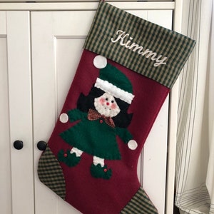 Christmas stocking with a girl elf hand-stitched to the front. Multiple hair colors to choose from. This Elf Christmas stocking is made of high quality felt, lined, personalized and hangs beautifully. Christmas stocking to treasure for years to come.