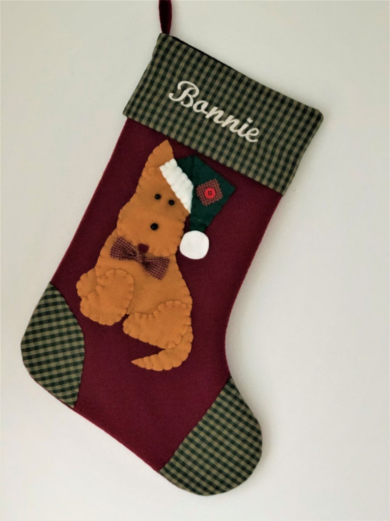 Terrier Christmas Stocking. Dog Christmas stocking with an adorable terrier on the front. Dog is wearing a stocking cap and hand stitched to the front. Stocking is made of high quality felt, lined, personalized and hangs beautifully. Optional colors