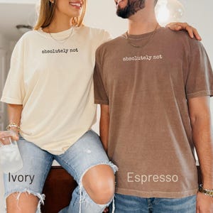 Cream and brown t-shirts with "absolutely not" text, worn by models.
