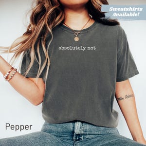Woman wearing a dark grey t-shirt with "absolutely not" printed in white.