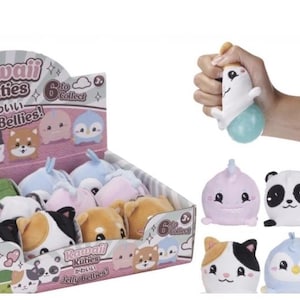 May include: A display box of Kawaii Kuties Jelly Bellies plush toys. The box features various animal designs, including a panda, a dog, and a penguin. A hand squeezes a white and blue plush toy. The text "Squeeze Me to See my Jelly Belly!" is visible.