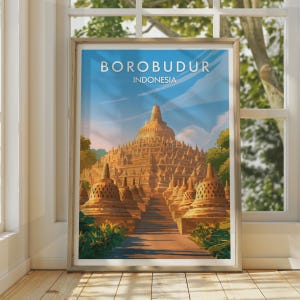 May include: A vertical travel poster print featuring a stylized illustration of the Borobudur temple in Indonesia. The artwork displays the stone structure with its iconic stupas under a blue sky, with the text BOROBUDUR INDONESIA at the top.