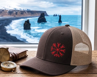 Könnte beinhalten: Eine braune Trucker-Cap mit einem roten, aufgestickten Vegvisir-Symbol auf der Vorderseite. Die Kappe hat eine einfarbig braune Front und ein beiges Netzgewebe an der Rückseite mit einem verstellbaren Verschluss. Das Motiv ist mittig platziert.