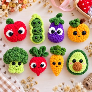 May include: A collection of eight crocheted plush toys shaped like fruits and vegetables, including a red apple, green peas, a purple aubergine, an orange, broccoli, a red radish, a carrot, and an avocado, all featuring black plastic eyes.