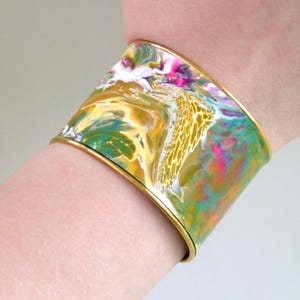 1.75" cuff bracelet with acrylic skin insert in gold, green pink and white. Adjustable brass plated gold.