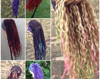 Könnte beinhalten: Eine Sammlung von sechs langen, bunten, synthetischen Dreadlocks, jede mit einer anderen Farbkombination. Die Dreadlocks werden auf Mannequins mit verschiedenen Stirnbändern präsentiert.