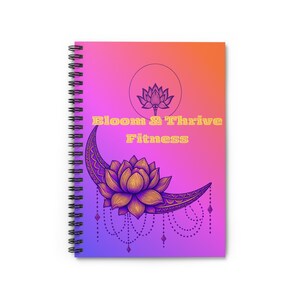 Op de afbeelding: Een spiraalgebonden notitieboek met een kleurverloop van oranje naar paars. De kaft toont een gele lotusbloem op een halve maan, een kleinere lotus erboven en de tekst Bloom & Thrive Fitness in gele letters.
