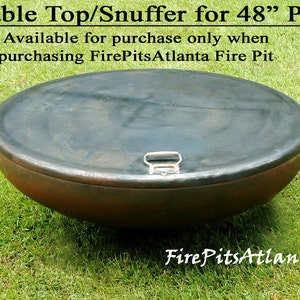 May include: A round, metal table top or snuffer for a 48-inch fire pit. The top is dark gray with a silver handle. The top is sitting on green grass.