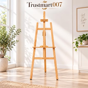 May include: A light brown wooden tripod easel featuring a central vertical support, an adjustable horizontal canvas tray, and a top clamp. The text Trustmart007 is displayed above the easel in a dark brown font with a small leaf icon.