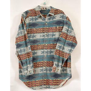 May include: A long-sleeved button-down shirt with a Southwestern-inspired pattern. The shirt features a mix of colors, including teal, red, yellow, and navy blue, with a repeating floral design. It has two chest pockets and buttoned cuffs.