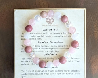 May include: A beaded stretch bracelet featuring alternating round beads in shades of pink, white, and translucent clear. The bracelet is displayed on a square card labeled Earth Gem Atelier with printed text describing Rose Quartz, Rainbow Moonstone, Rhodonite, and Clear Quartz.
