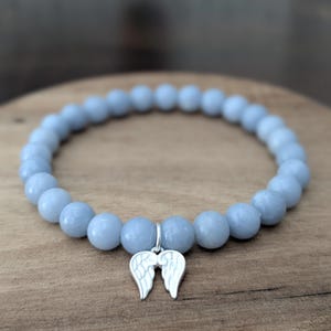 Puede incluir: Pulsera de cuentas azul claro con un dije plateado en forma de alas de &aacute;ngel. La pulsera est&aacute; hecha de cuentas redondas de color azul claro. El dije est&aacute; sujeto a la pulsera con un peque&ntilde;o lazo plateado.