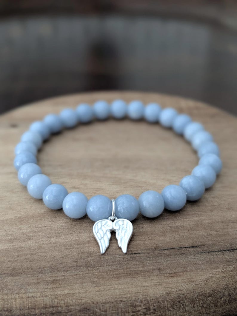 Puede incluir: Pulsera de cuentas azul claro con un dije plateado en forma de alas de &aacute;ngel. La pulsera est&aacute; hecha de cuentas redondas de color azul claro. El dije est&aacute; sujeto a la pulsera con un peque&ntilde;o lazo plateado.