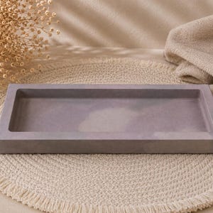 May include: A rectangular tray with a smooth, matte finish in a muted lavender-gray tone. The tray features a flat base and raised, thick edges, creating a shallow, open basin design with a clean, uniform appearance throughout the surface.