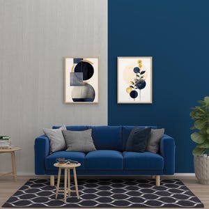 May include: A living room scene featuring a blue velvet sofa, gray throw pillows, and a patterned rug. Two framed abstract art pieces hang on the wall. A small wooden side table and a potted plant complete the decor.