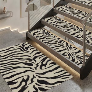 May include: A zebra-print rug and matching stair treads. The rug is rectangular, and the stair treads are installed on a wooden staircase. The zebra pattern features black stripes on a cream background. The staircase has a metal railing.