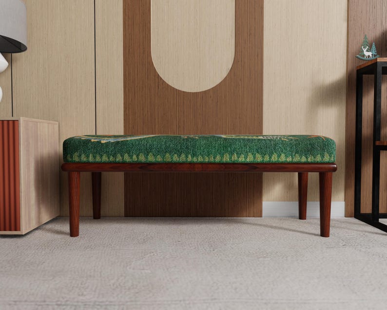 May include: A mid-century modern bench with a rectangular green patterned cushion and dark brown wooden legs. The bench is set against a neutral-toned wall with a decorative design.