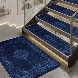 May include: A set of navy blue rugs and stair treads with an ornate, faded floral pattern. The rugs are rectangular and the stair treads are long and narrow, designed to fit each step. The stairwell has a modern design with metal railings.
