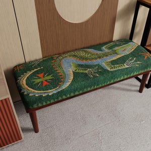 May include: A green bench with a lizard design. The lizard is depicted in shades of blue, orange, and green. The bench has dark brown legs and a rectangular shape. The lizard design is centered on the bench's top surface.