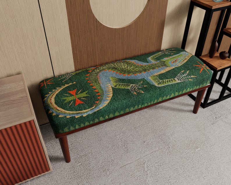 May include: A green bench with a lizard design. The lizard is depicted in shades of blue, orange, and green. The bench has dark brown legs and a rectangular shape. The lizard design is centered on the bench's top surface.