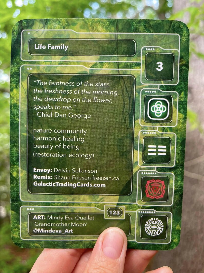 Puede incluir: Una tarjeta coleccionable rectangular con un fondo de bosque verde. La tarjeta presenta el texto Life Family, una cita de Chief Dan George y cr&eacute;ditos para Envoy Delvin Solkinson, Remix Shaun Friesen y la artista Mindy Eva Ouellet.