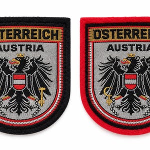 May include: Two embroidered patches featuring the Austrian coat of arms, a black eagle with a red and white shield on its chest, gold crown, sickle, and hammer. The text OSTERREICH and AUSTRIA is embroidered in black on a grey background with borders.