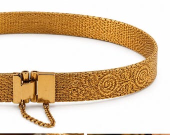 May include: A gold-toned metal choker necklace featuring a fine mesh texture and a repeating embossed circular floral pattern. The piece includes a rectangular hinged clasp mechanism at the front and a small dangling safety chain attached below.