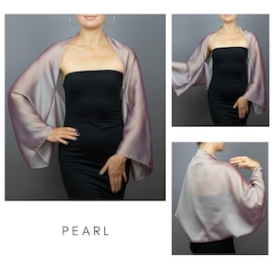 Pu&ograve; includere: Uno scialle di seta perlata con ampie maniche, nei toni del lavanda e rosa, indossato sopra un abito nero. La parola "PEARL" &egrave; stampata in un carattere semplice nella parte inferiore dell'immagine.