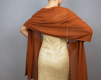 May include: A rust-colored sheer shawl draped over a gold lace dress.