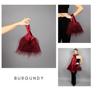 May include: Burgundy satin clutch with feather trim. The clutch is held by a hand in the image. The word "BURGUNDY" is displayed in the image. The clutch is a deep red colour.