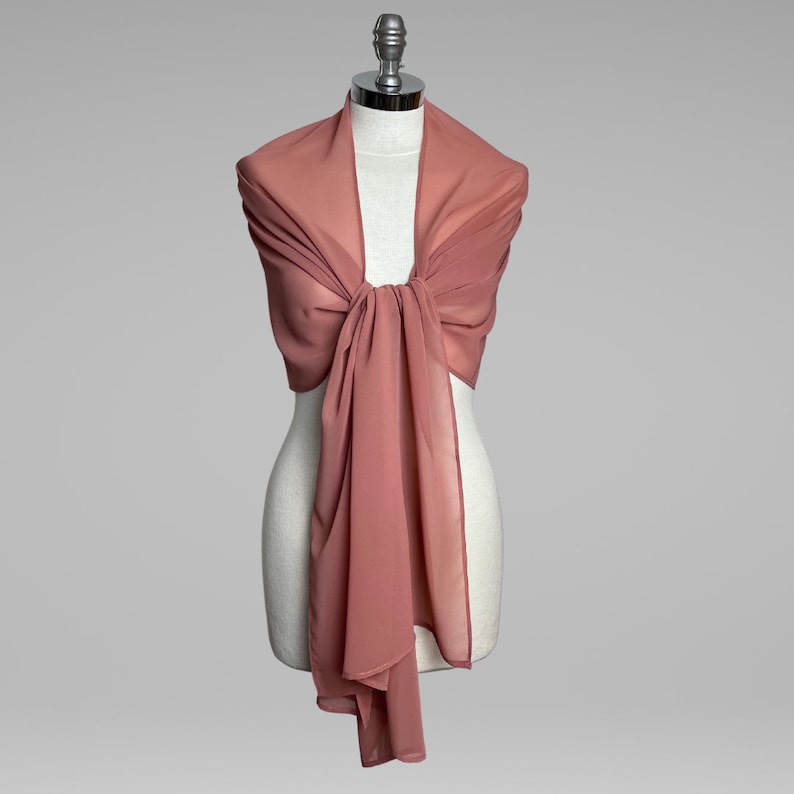 May include: A dusty rose chiffon shawl draped over a mannequin. The shawl is tied in a knot at the neck and hangs down to the waist.