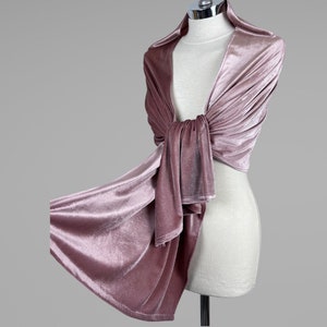 May include: A soft, dusty rose velvet shawl draped over a mannequin. The shawl is long and flowing, with a delicate sheen.