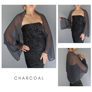 Pode incluir: Um xale transparente cinza carv&atilde;o com mangas compridas, usado sobre um vestido preto sem al&ccedil;as. A palavra "CHARCOAL" est&aacute; impressa em branco na parte inferior. A imagem &eacute; uma foto de produto de moda, mostrando a queda e o estilo da pe&ccedil;a.