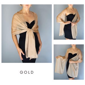 May include: A gold-toned, sheer shawl worn over a black dress. The shawl is knotted at the front, creating a layered look. The word "GOLD" is printed in a simple font at the bottom of the image. Additional views of the shawl are shown.